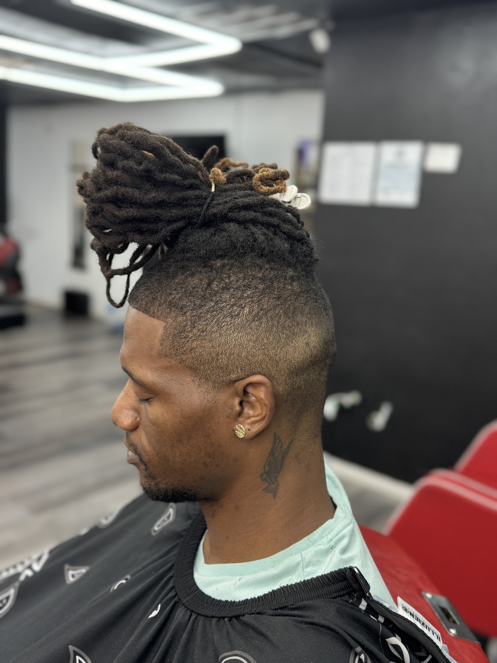 Man with dreadlocks pulled into a top bun and clean burst fade on the sides
