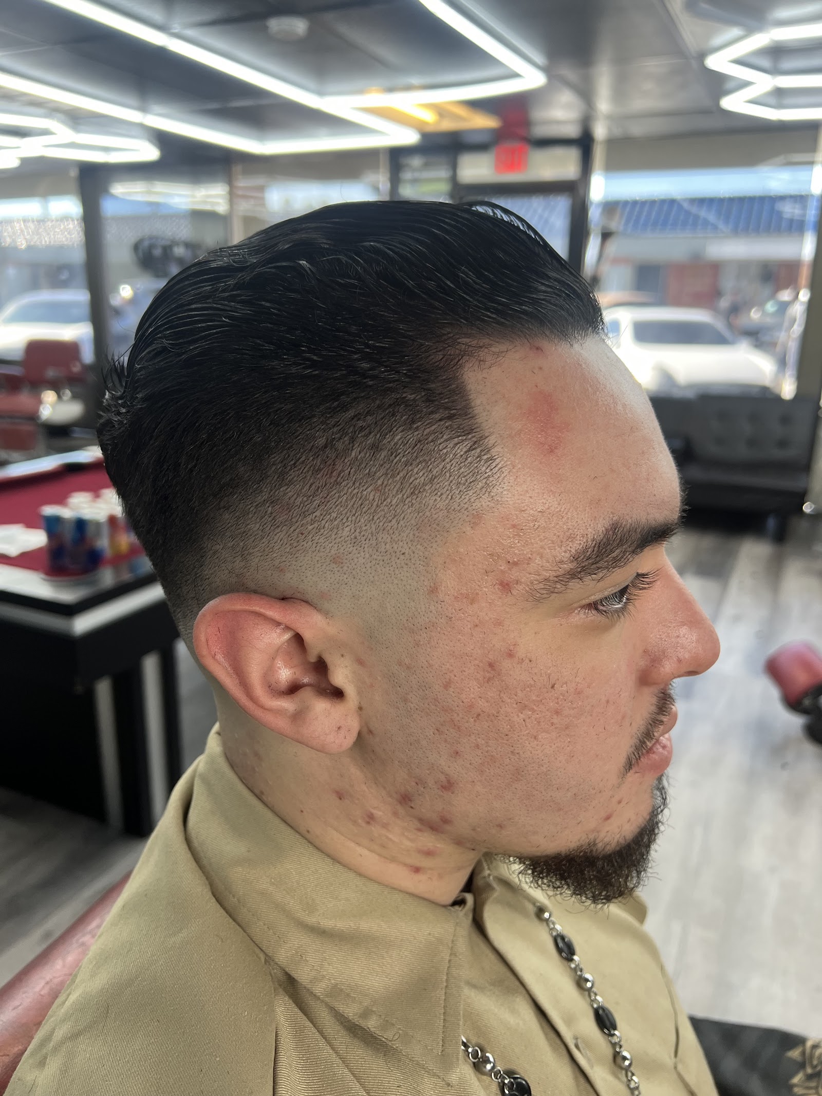 Side profile of a men's slicked-back haircut with a skin fade