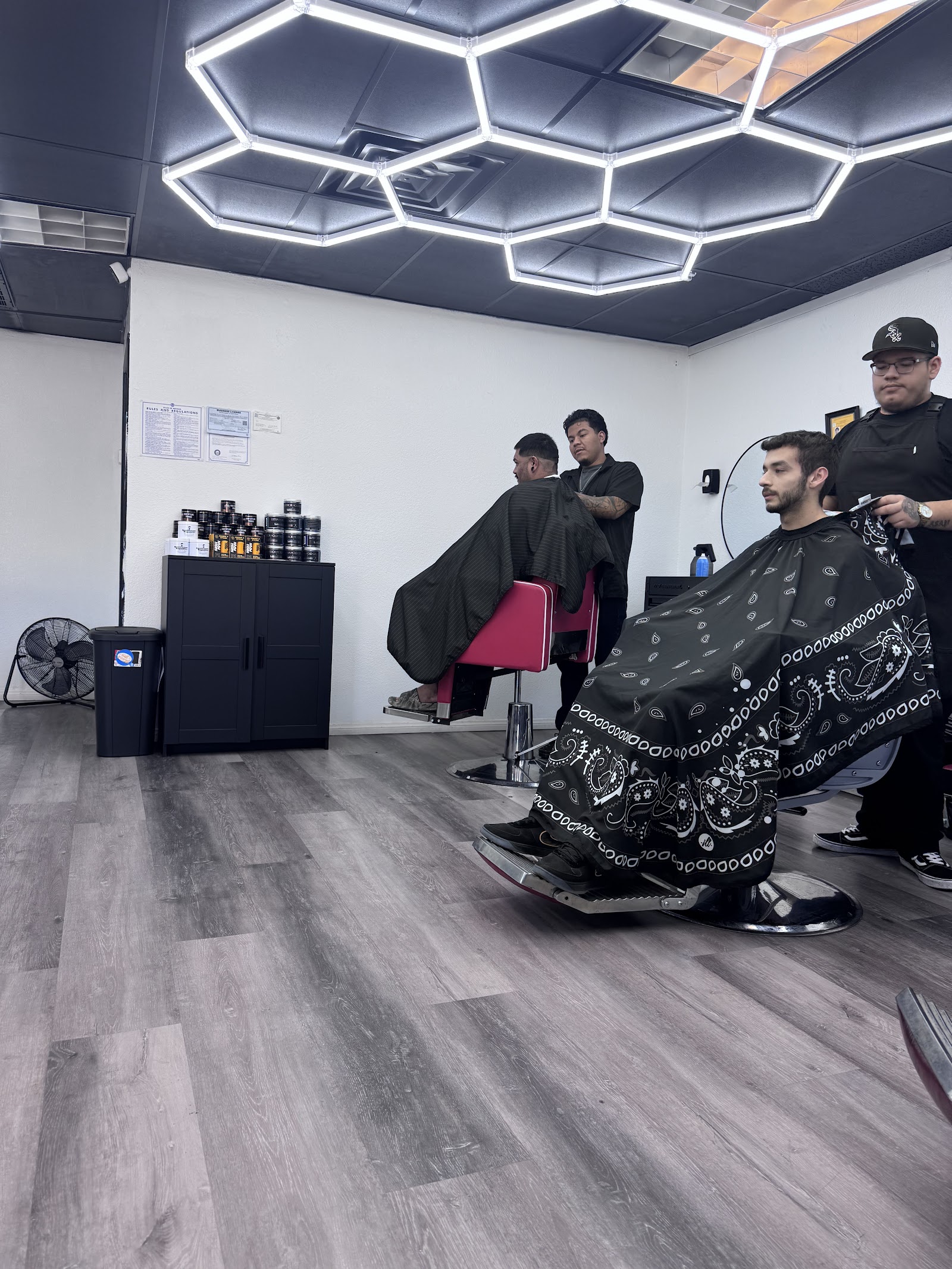 Barbershop interior with hexagon LED lighting and barbers cutting clients' hair